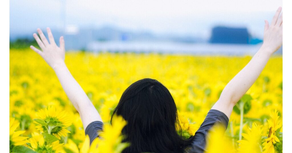 万歳をする女性　明るい雰囲気　花畑にいる